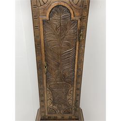 19th century carved oak longcase clock, projecting cornice over guilloche carved frieze, square brass dial with silvered Roman chapter ring and calendar aperture, decorated with ornate mask cast spandrels, the trunk door and base carved with potted plant, twin train driven eight day movement striking on bell