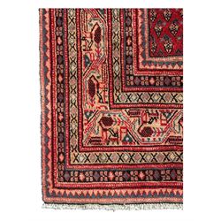 Persian Arak crimson ground rug, the field decorated with repeating Boteh motifs within geometric guard stripes