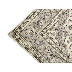 Persian Kashan ivory ground carpet, floral central medallion surrounded by trailing leafy branches and palmettes, floral pattern spandrels and matching border, within guard stripes