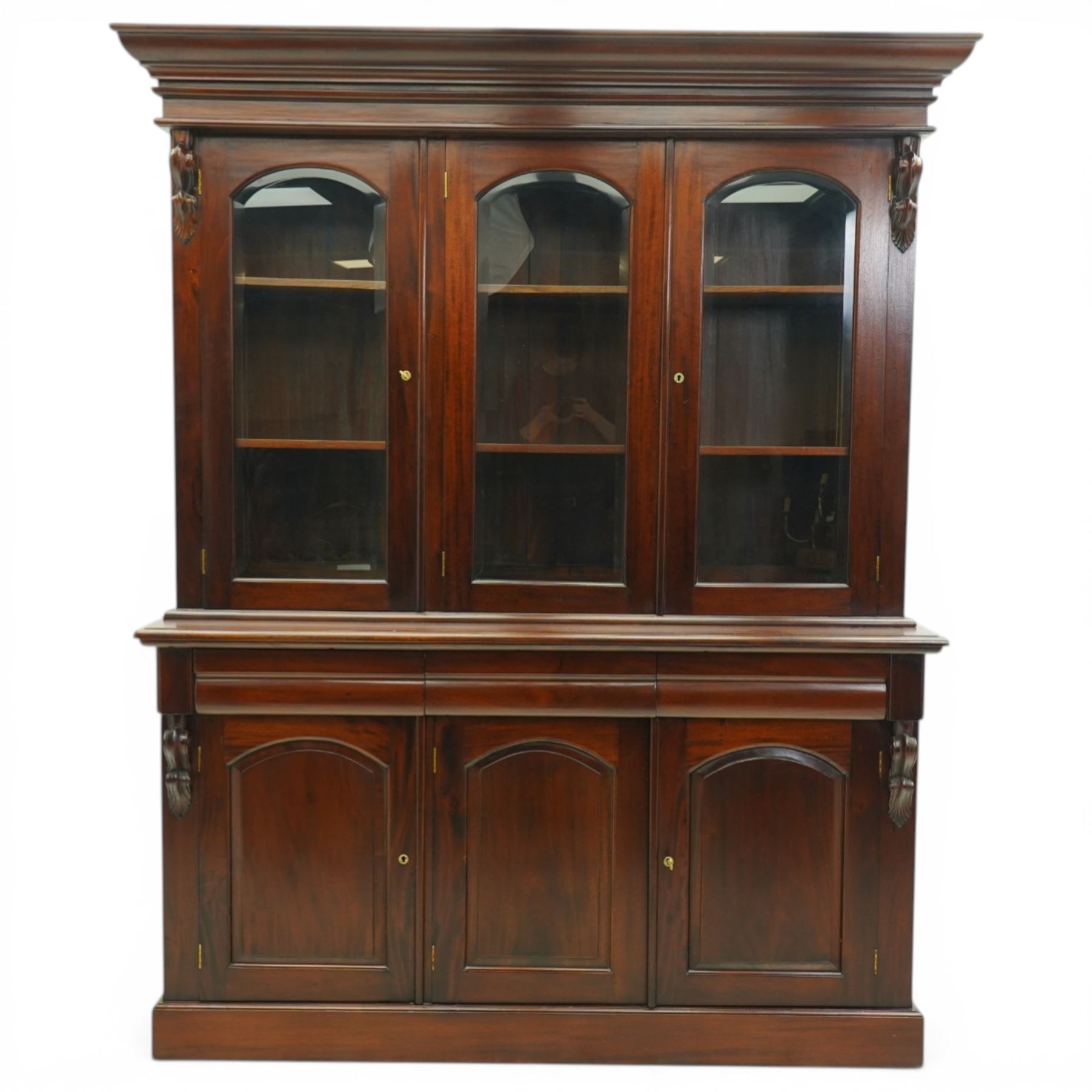 Victorian revival hardwood dresser, projecting moulded cornice above three glazed doors enclosing shelves, moulded top over three drawers and three panelled cupboard doors, flanked by applied carved scroll brackets, on plinth base,