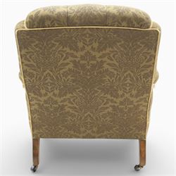 Late Victorian open armchair, in the manner of Howard & Sons, with deep buttoned seat and back upholstered in green damask fabric, with fringed detail to the lower arms, raised upon turned front legs with brass castors