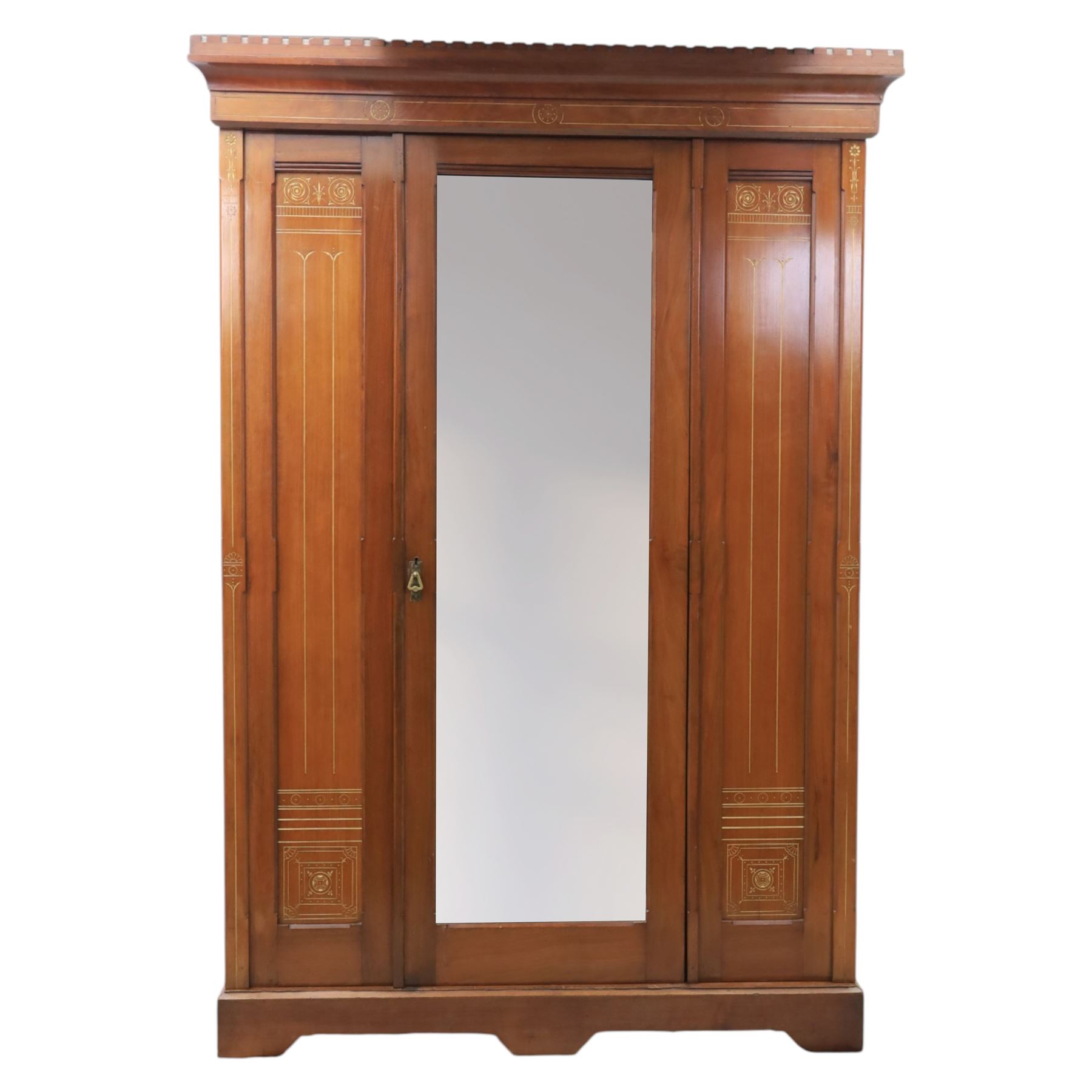 Aesthetic Movement walnut parcel gilt wardrobe, the crenellated top, above central mirrored door opening to reveal hanging space, four opened and two closed draws