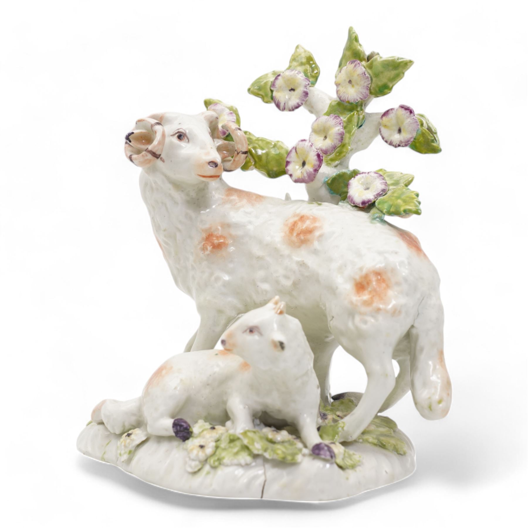 Two 18th century Derby porcelain groups modelled as a ram standing before bocage above a recumbent lamb, upon flower encrusted base, H15cm and two further Derby figures modelled as a ram and cow and calf (3)