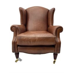 Laura Ashley - wingback armchair, upholstered in brown leather, on turned and fluted supports with brass castors