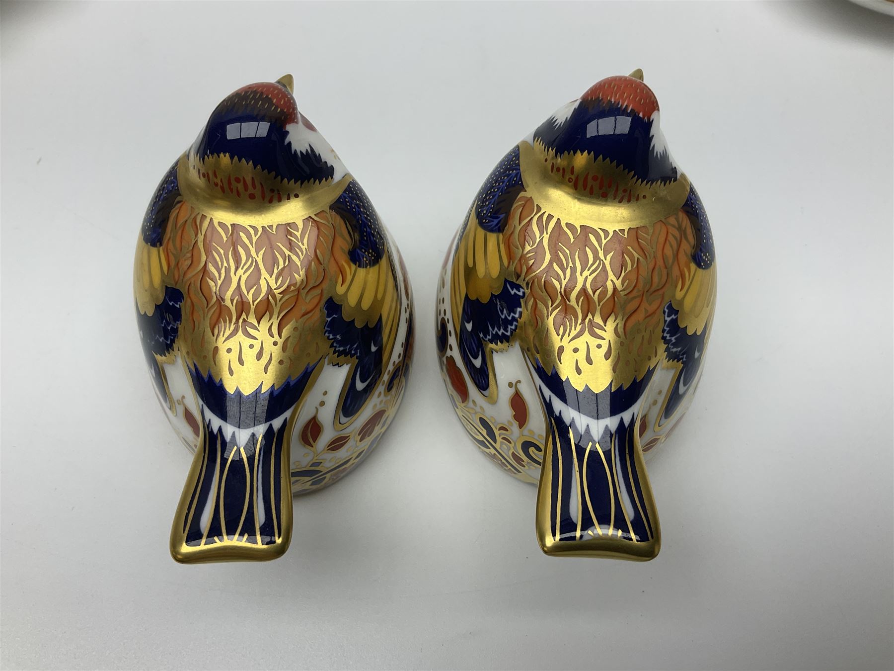 Two Royal Crown Derby Goldfinch Nesting paperweights with silver stoppers, together with two Royal Crown Derby imari pin dishes, largest dish D13cm