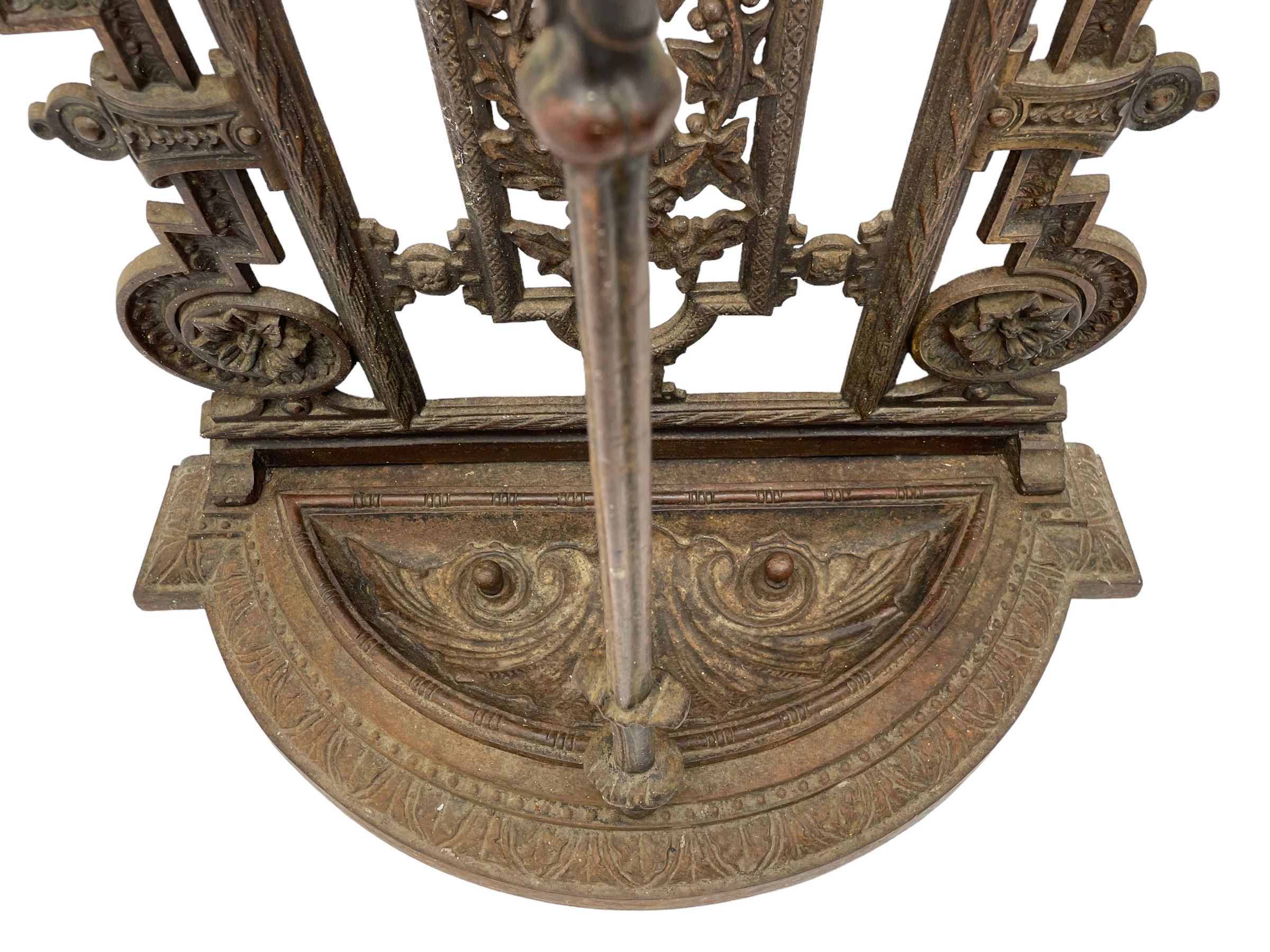 19th century cast iron hallway hat and coat stand, the arched frame decorated with overlapping foliage, central oval mirror surrounded by trailing oak leaves and acorns, with extending umbrella and stick stand, the curved plinth base decorated with acanthus leaves, with impressed and mounted R.d. lozenges