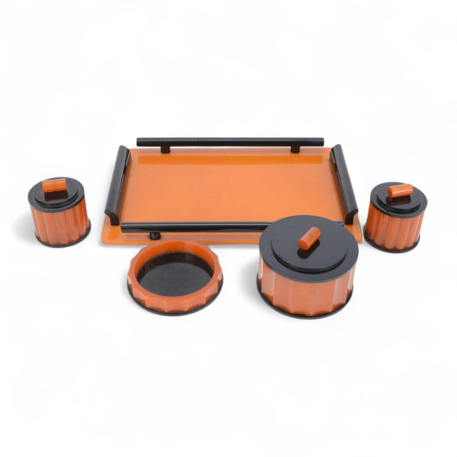 Art Deco phenolic Bakelite dressing table set, comprising three circular jars with lids and a pin dish, all upon a rectangular tray with black handles tray 30x19cm 