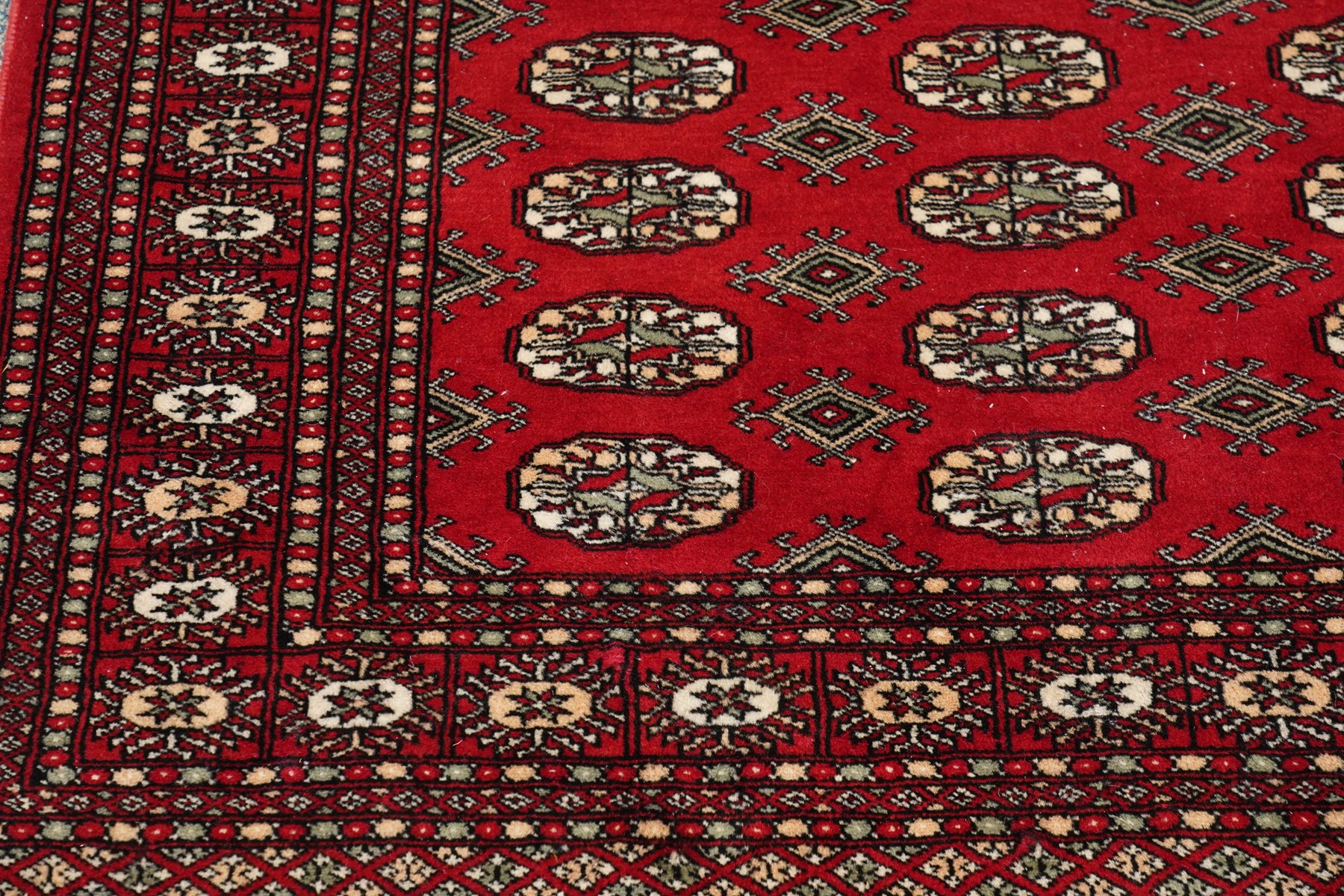 Two Afghan Bokhara crimson ground rugs, the fields decorated with repeating Gul motifs with geometric guard bands (126x190 & 157x250)
