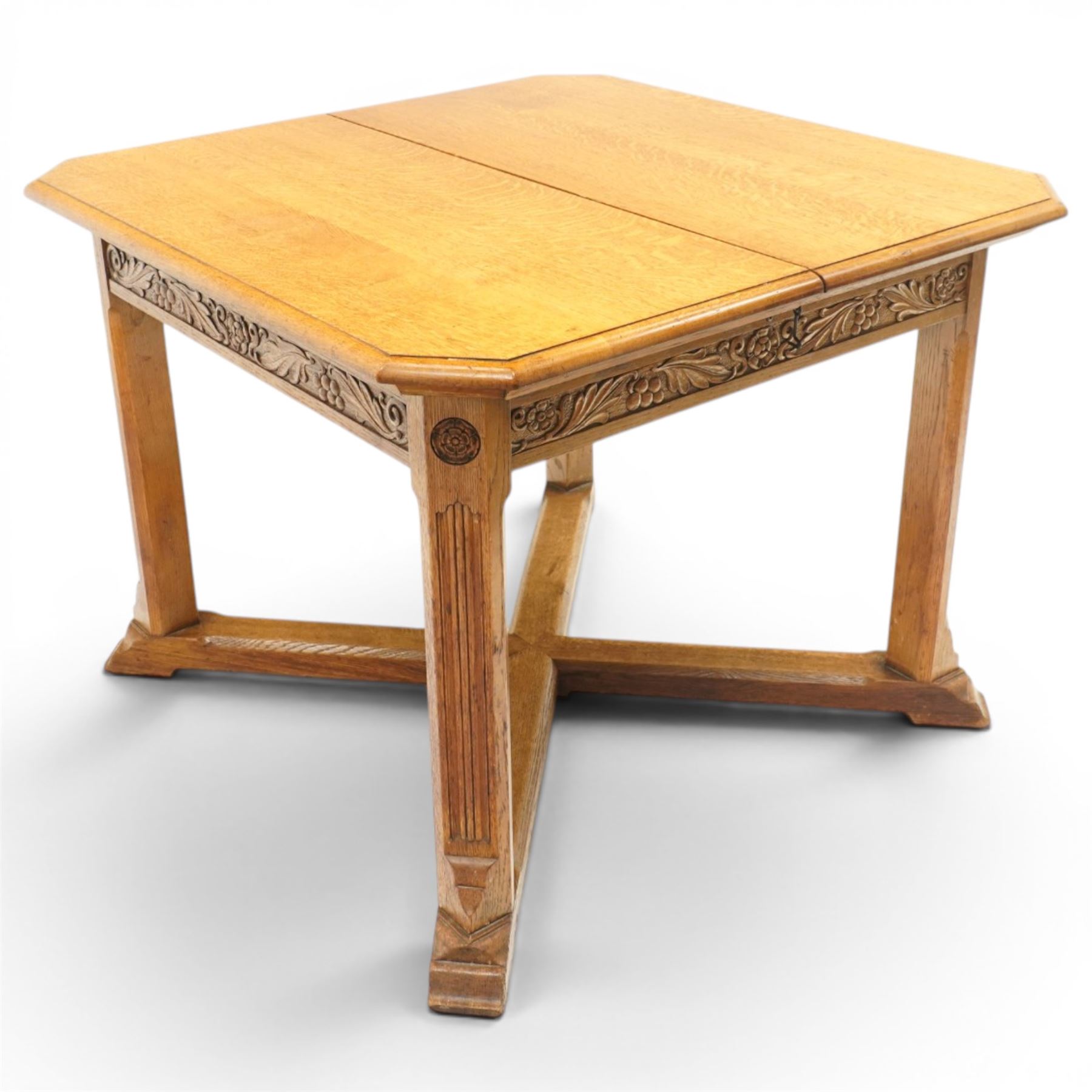 Waring & Gillow - Arts and Crafts oak draw-leaf extending dining table rectangular moulded top with chamfered corners, two additional leaves, carved frieze over fluted section supports, united by low X-shape stretchers