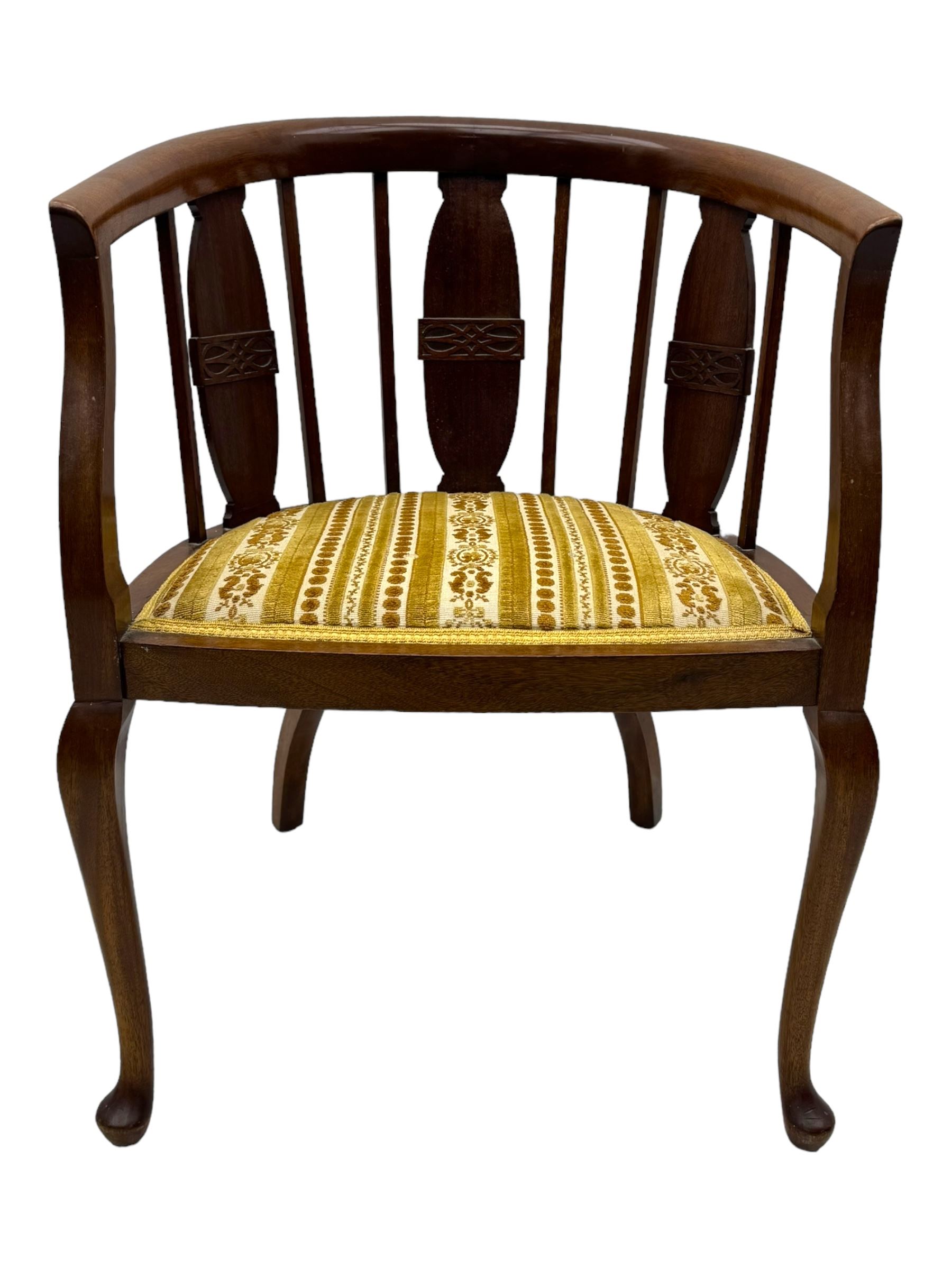 Late Victorian mahogany framed tub chair, rounded backrest with vertical splats and three carved oval medallions, upholstered seat in yellow patterned fabric, on cabriole supports