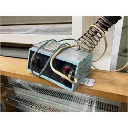 Six shelved cabinets for displaying ‘00’ gauge locomotives comprising plain plywood and white painted examples with track applied to various shelves, largest H63cm, W107cm, D27cm; Collection of tools for building model locomotives to include Weller PU-2D Soldering Pencil and Standard Tip Soldering Iron 20W/230V, Humbrol Modellers Airbrush, Power Supply Units and two wooden chests one of which housing a collection of tools including tweezers, scalping tools, wrenches etc 