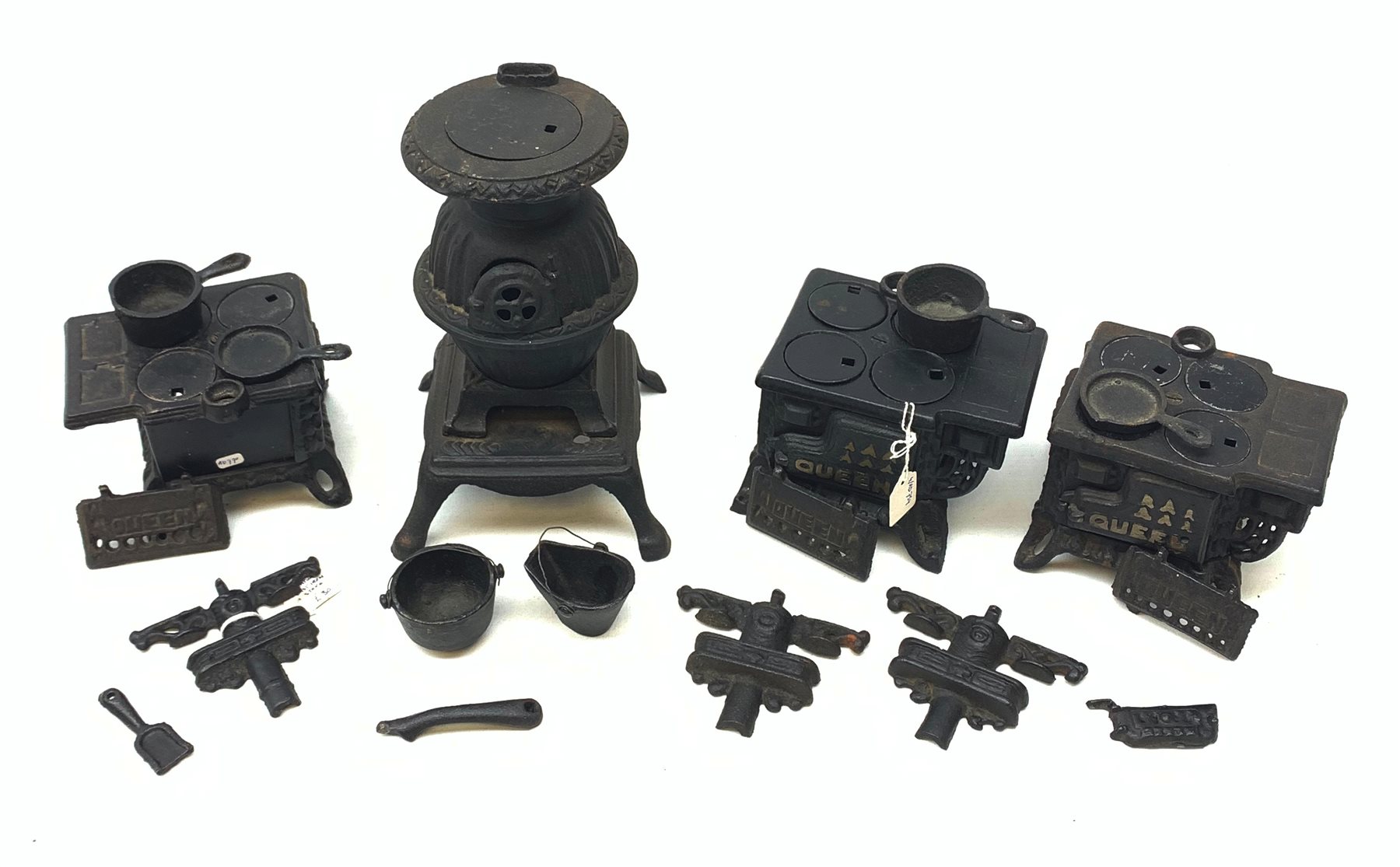 Three miniature cast iron salesman sample stoves, together with a miniature cast iron pot belly stove. 