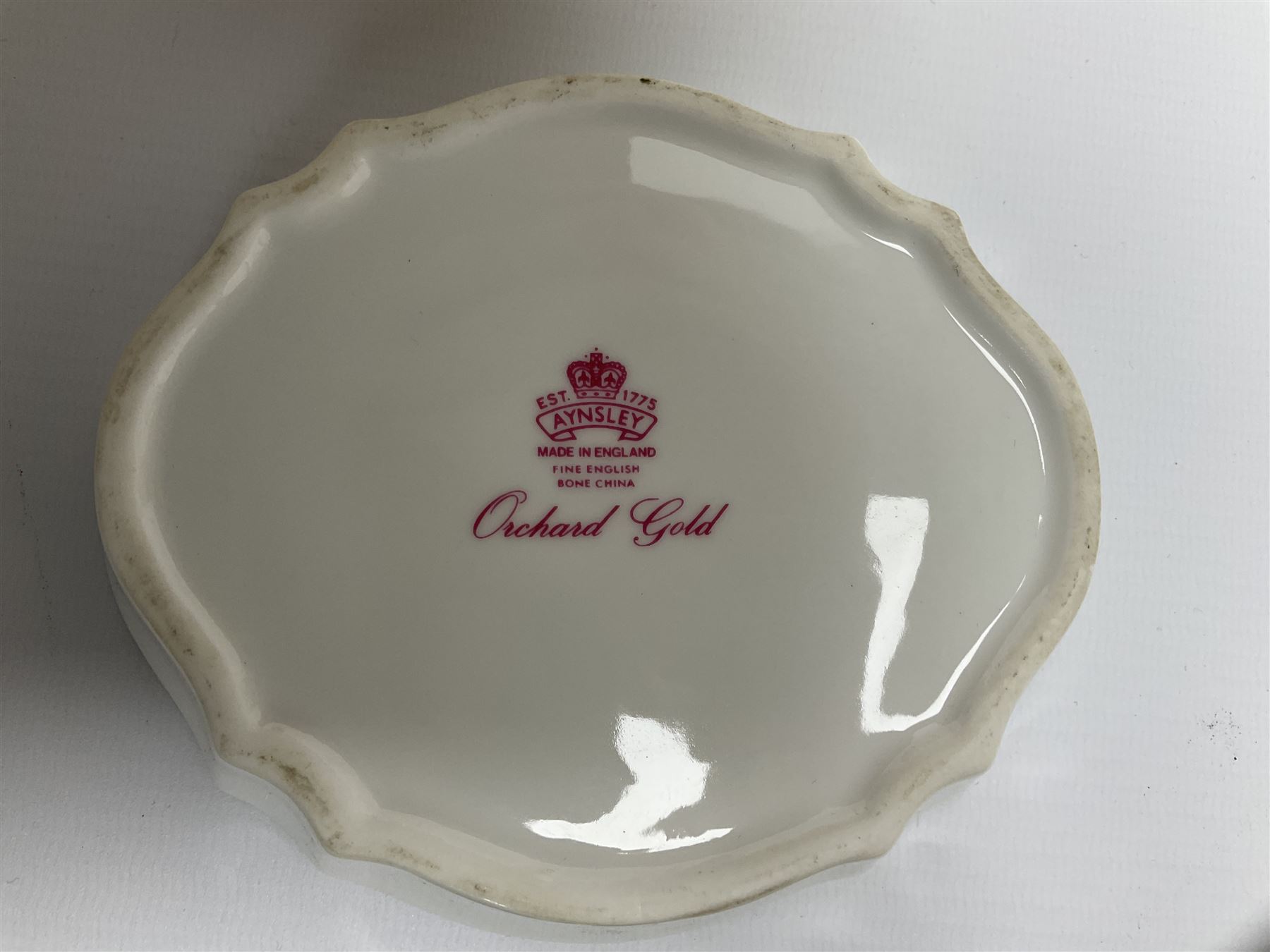 Collection of Aynsley Orchard Gold pattern wares, comprising lamp base, three jars and covers, six vases or various size and form, large jug, lidded dish, pair of cruets, pair of candlesticks, mug, two pin dishes, lobed dish, tea cup, saucer, size plate, and cake plate, and two further cups and saucers, each cup decorated with central Orchard Gold reserve to the interior against a mottled pink or green ground. 