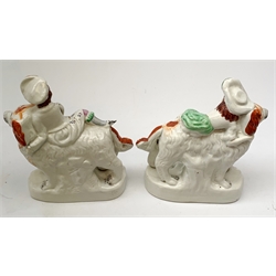 Pair of Victorian Staffordshire figures, modelled as two children, probably Queen Victoria's children, seated upon the backs of two large dogs, each upon an oval base, tallest H22cm