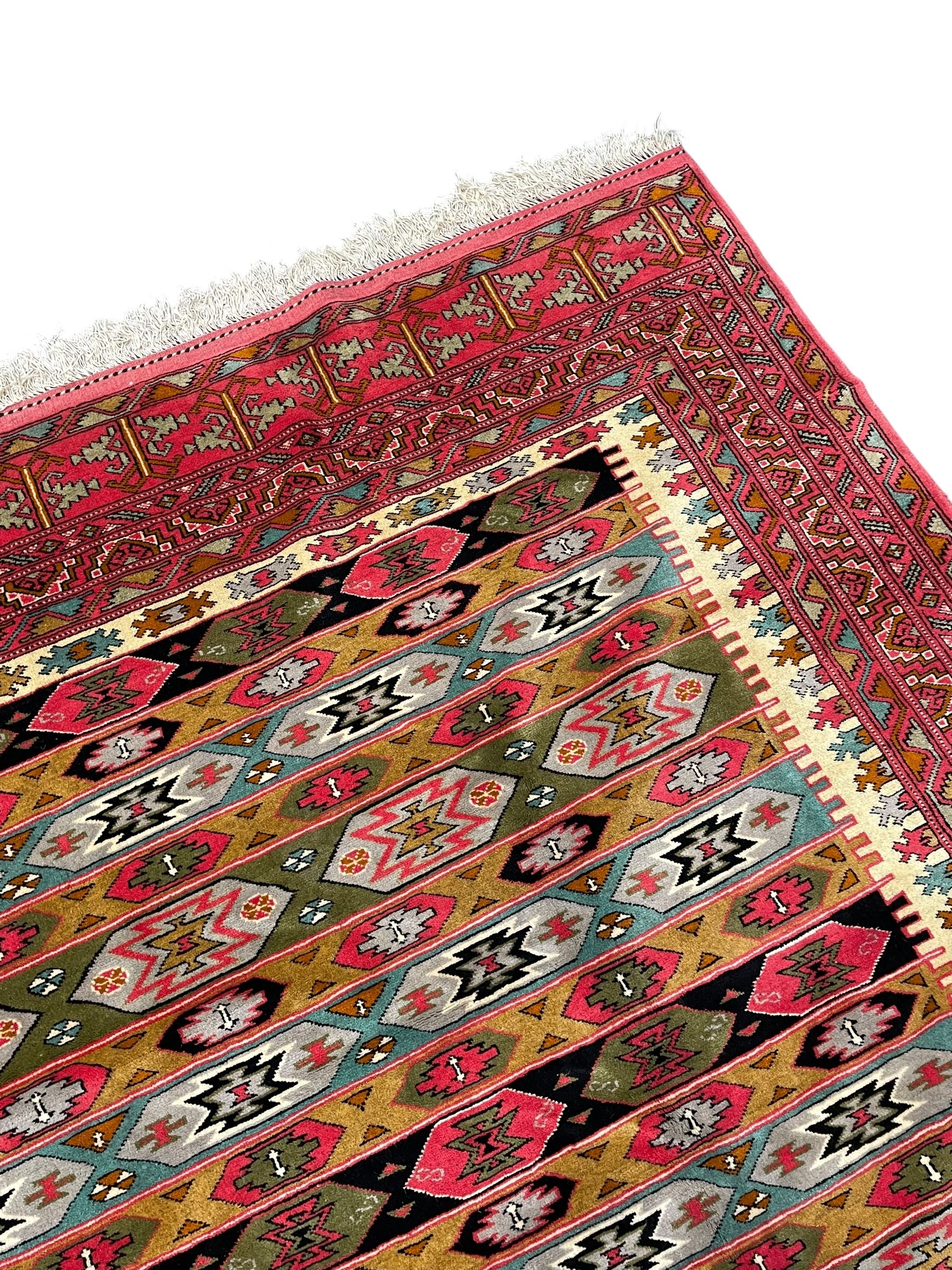 Persian red ground rug, the field divided into horizontal rows and decorated with geometric motifs, intricately pattern borders and end panels