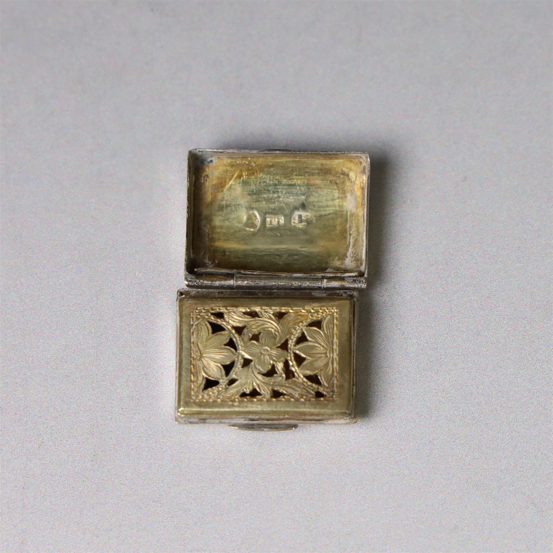 Two George III silver vinaigrettes, the first of rectangular form, the hinged cover modelled as a strap and engraved with acanthus leaves and flower heads, opening to reveal a foliate pierced gilt grille, hallmarked IT, Birmingham 1792, W2.5cm, the second of oval form, the hinged cover engraved 'C M Church' within a foliate border, opening to reveal diamond pierced gilt grille, hallmarked Cocks & Bettridge, Birmingham 1805, W2.5cm