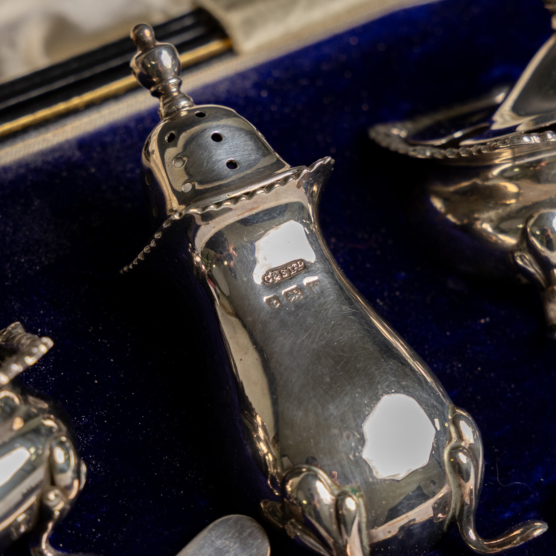 1920s silver three piece cruet set, comprising mustard pot and cover, pepper shaker and open salt, together with two matched silver cruet spoons, all hallmarked, contained within fitted tooled leather case
