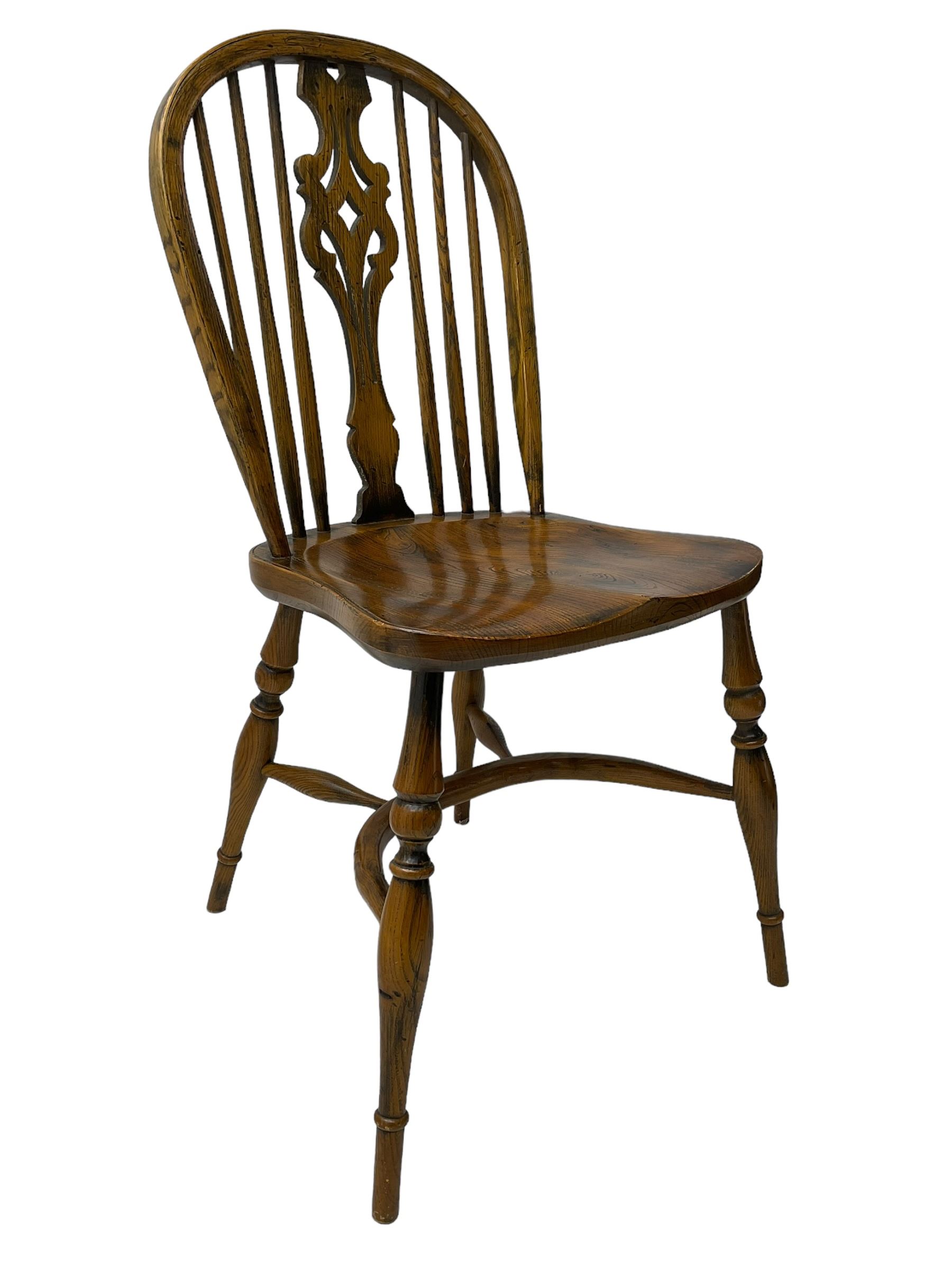 Set of four elm Windsor dining chairs, high hoop and stick back with shaped pierced splat, over shaped saddle seat, raised on ring turned supports joined by crinoline stretcher