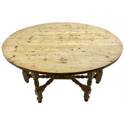 Traditional stripped pine dining table, circular drop-leaf top over double gate-leg action base with turned supports united by turned stretchers