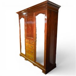 Edwardian mahogany triple combination wardrobe, the moulded cornice above a central panel door inlaid with foliate detail, flanked by full length mirrored doors, the interior fitted with hanging compartments and a central bank of two short and three long drawers, raised on a shaped bracket feet