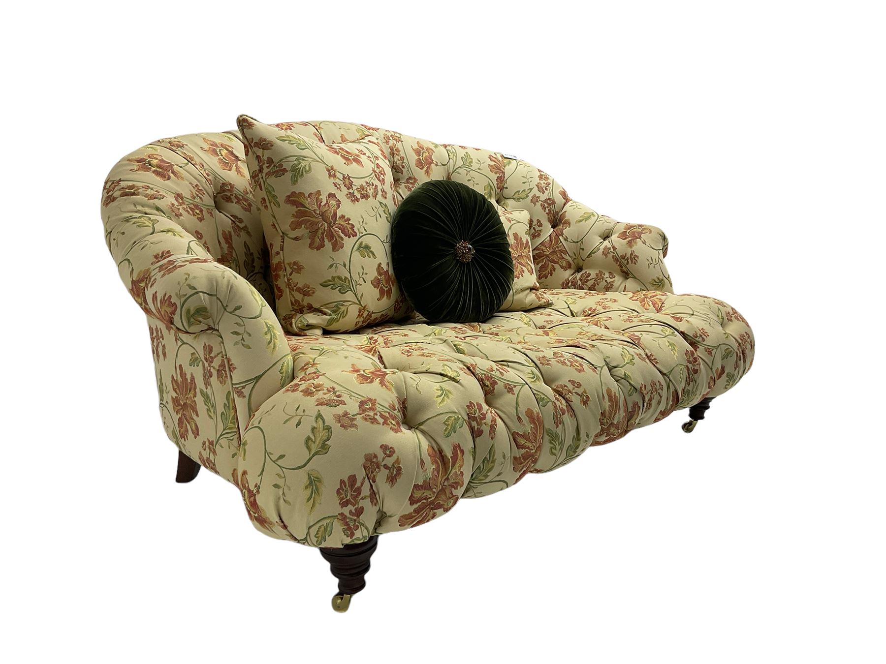 Victorian style two seat sofa, upholstered in beige ground floral floral pattern fabric, with scatter cushions, turned feet with brass castors