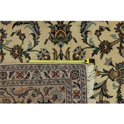 Central Persian Kashan carpet, ivory ground, field with an all-over design of scrolling palmettes and floral sprays in blue and terracotta within a beige ground and pale blue floral border