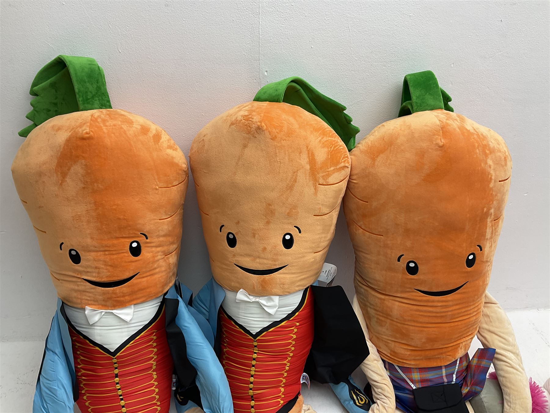 Three large ALDI Kevin carrots and giant unicorn stuffed toy together with quantity of smaller carrots