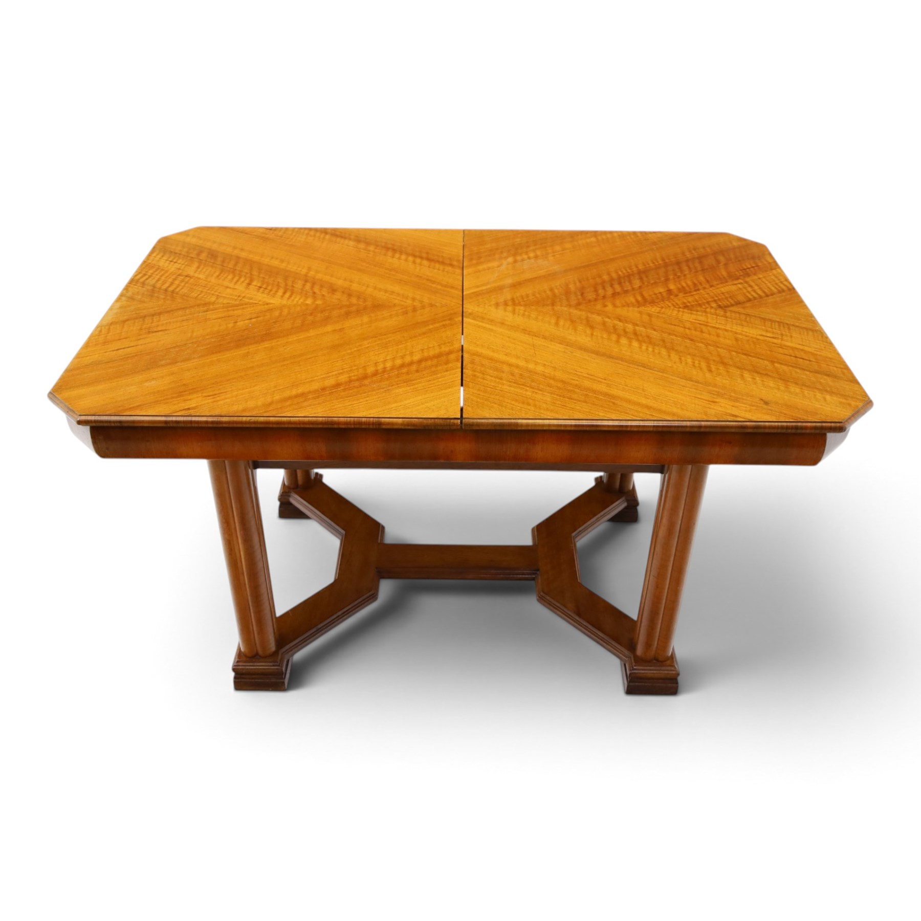 Art Deco walnut extending dining table, book-matched veneered shaped top, raised on cluster-column supports, united by stretchers, additional leaf extends to 185cm  