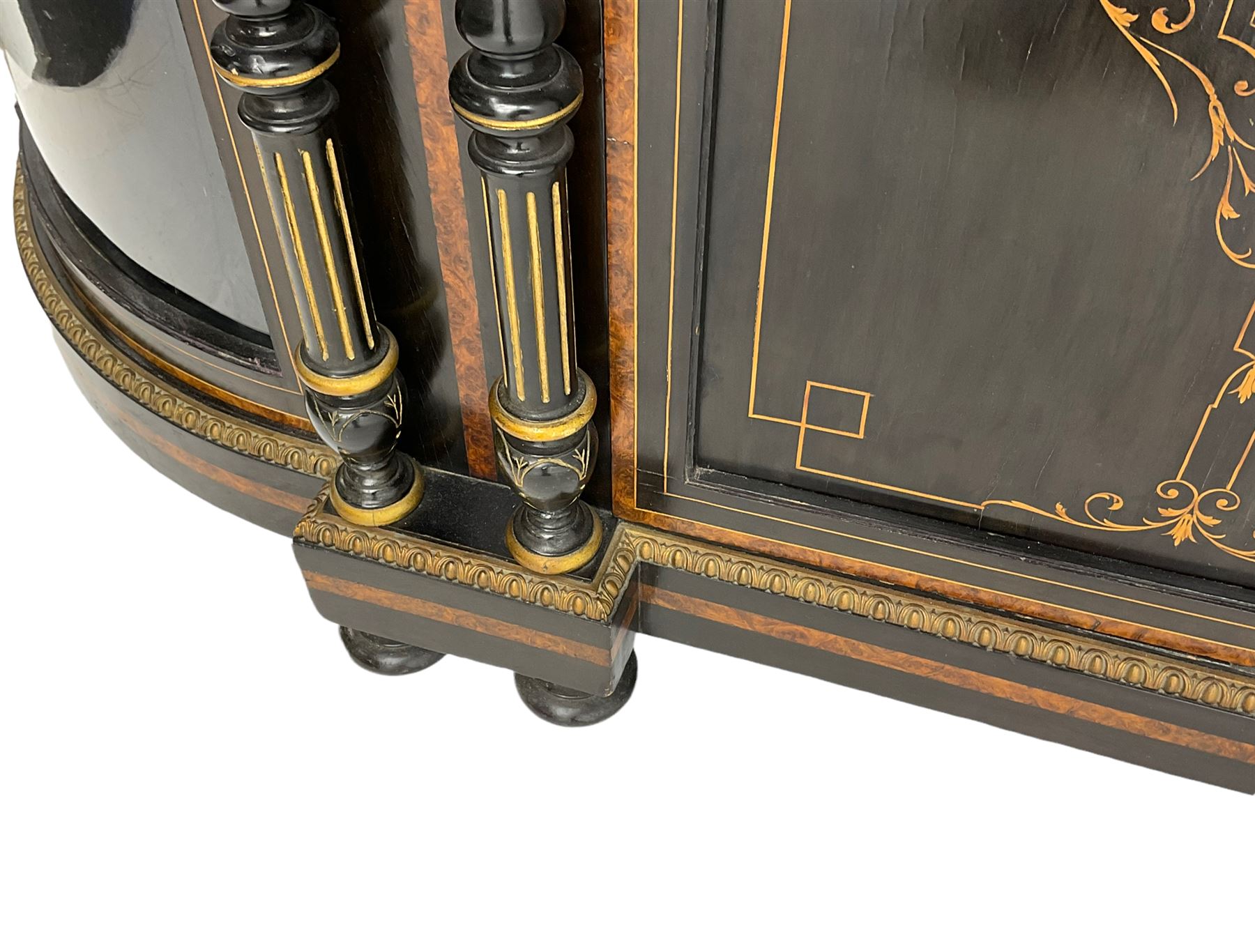 Victorian ebonised and inlaid credenza, break-front with curved ends, the front fitted with two curved glazed doors and central panelled door, inlaid with scrolling foliate and star motifs, quadruple turned and fluted pilasters to front, gilt egg and dart moulded edge on plinth base with figured walnut band, on turned feet