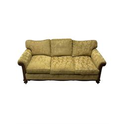 Early 20th century mahogany framed three-piece lounge suite - three-seat camelback sofa (W203cm, D105cm); pair of matching armchairs (W95cm, D96cm); upholstered in neutral foliate pattern fabric, carved with trailing leafy branches, ball and claw carved feet with brass castors 