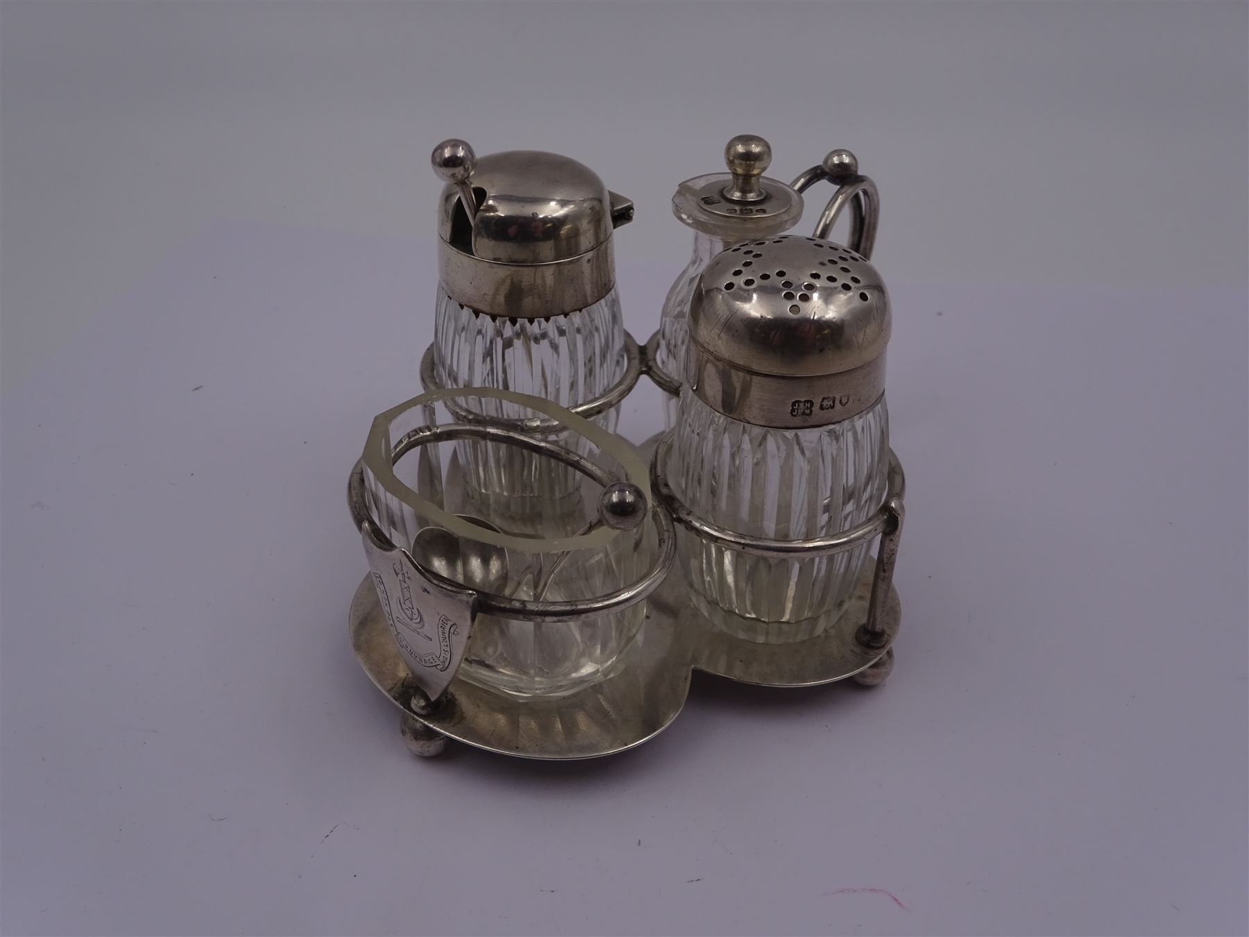 Late Victorian silver mounted four piece cut glass cruet set on stand, comprising pepper shaker, open salt, mustard pot and vinegar bottle, the silver stand with shield engraved with the Workman family crest, hallmarked Hukin & Heath, London 1899, including bottles H7cm