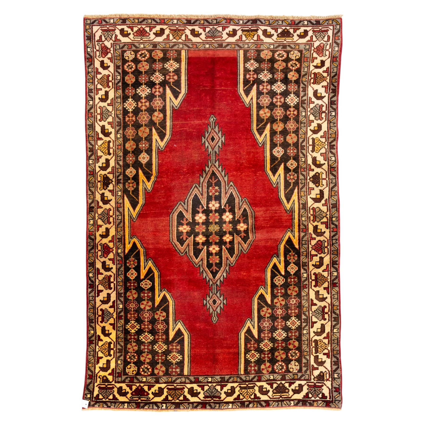 West Persian Mazlaghan hand-knotted rug, madder red field with central stepped lozenge medallion with pendant motifs flanked by angular serrated spandrels filled with small geometric devices, enclosed within multiple borders featuring stylized floral and geometric motifs, with cotton fringe ends 