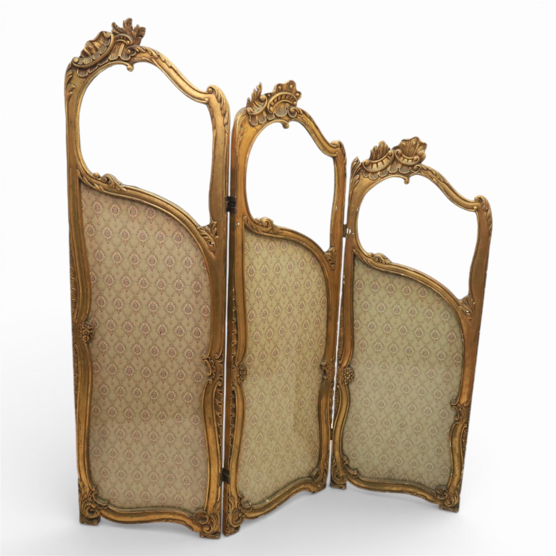 Rococo style giltwood three-panel dressing screen, each panel with shaped and scroll carved frame decorated with shell and foliate motifs, the upper sections glazed, the lower sections upholstered in patterned fabric, hinged to form a folding screen