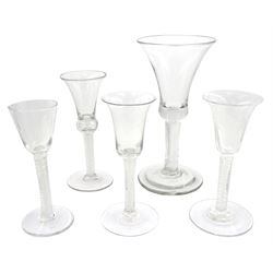 Five 18th century and later drinking glasses, comprising large example with bell shaped bowl upon single series air twist stem and spreading circular foot, H20.5cm, example with bell shaped bowl engraved with roses upon a double series opaque twist stem and spreading circular foot, H15.5cm, and a further three, two with bell shaped bowls, and one with funnel bowl, each upon double series opaque twist stem and spreading circular foot 
