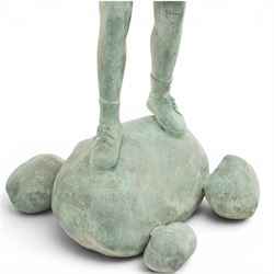 After Eneri Prosperi, bronze garden child statues, depicting children balancing on rock-form bases, the boy in shirt and shorts, the girl in dress with raised arms, surrounded by loose rounded pebble elements