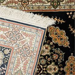 Persian-inspired Qom-style silk rug, deep indigo ground, profusely decorated with foliate motifs and a central medallion, with cotton fringe ends 