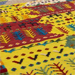South West Persian Qashqai flatweave kilim, field arranged in bold horizontal bands of saffron yellow, madder red and deep green, decorated stylized tribal motifs including birds, animals, fish and schematic tree devices, composition arranged in a stepped asymmetrical format, with fringe ends 