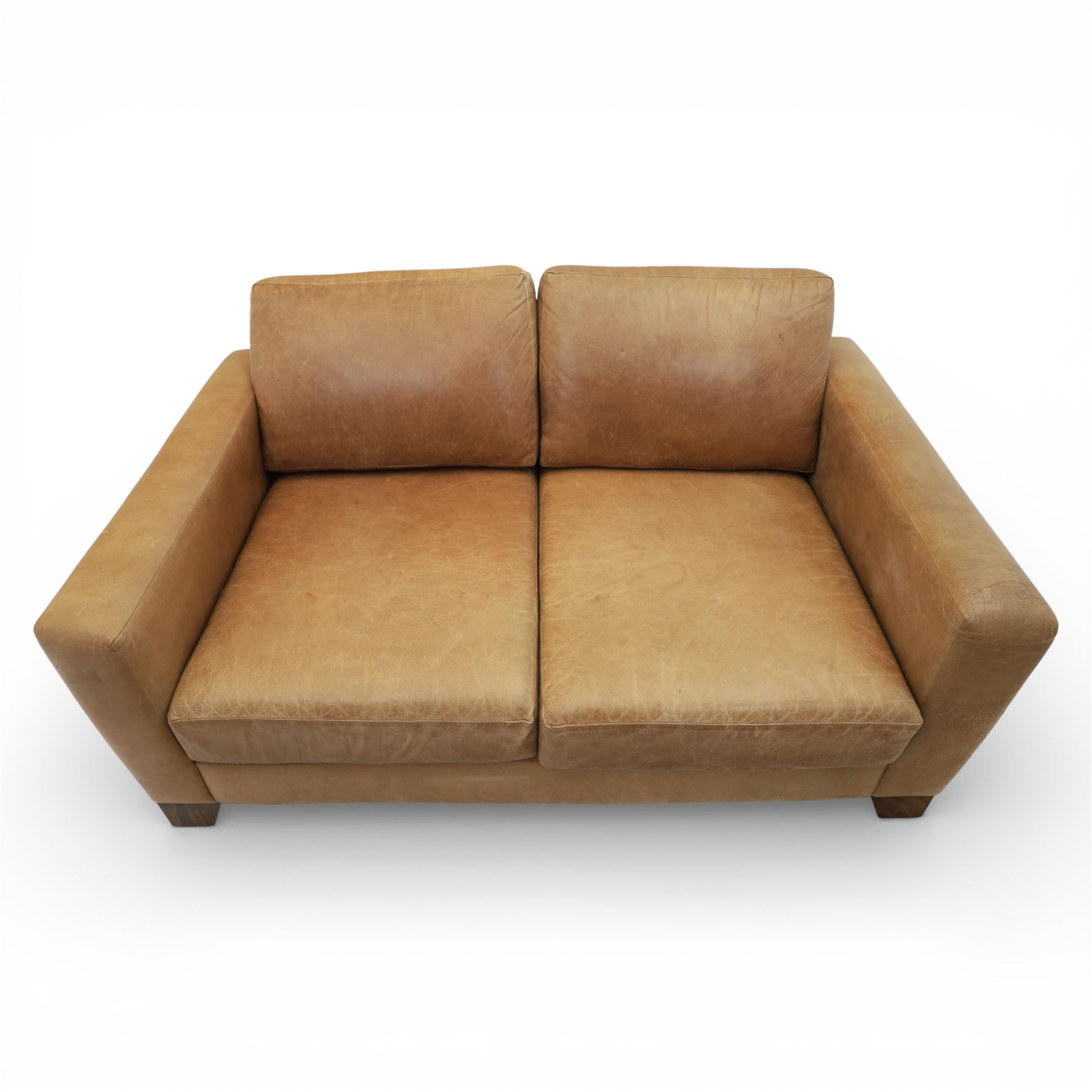 Modern two seat sofa in tanned leather, loose seat and base cushions, block arm rests above dark stained block supports 