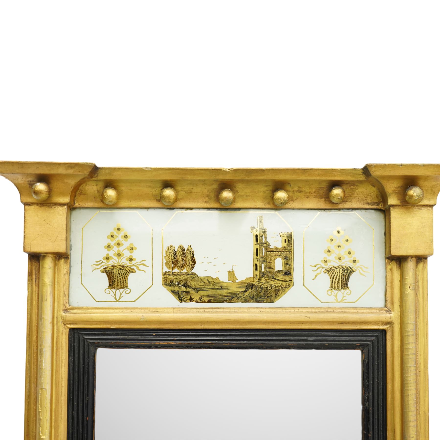 Regency giltwood pier mirror, projecting moulded cornice with ball mounts, the glazed frieze decorated with coastal ship and castle scene and flanked by to floral baskets, ebonised reeded slip enclosing bevelled mirror plate