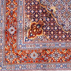 North Eastern Persian Moud hand-knotted carpet, field with central lobbed medallion with radiating serrated palmettes and spandrels in a densely worked all-over ground of small floral rosettes and geometric blossoms within a wide floral border flanked by multiple guard borders in a palette of indigo blue, ivory, terracotta, turquoise, and muted gold, with cotton fringe ends 