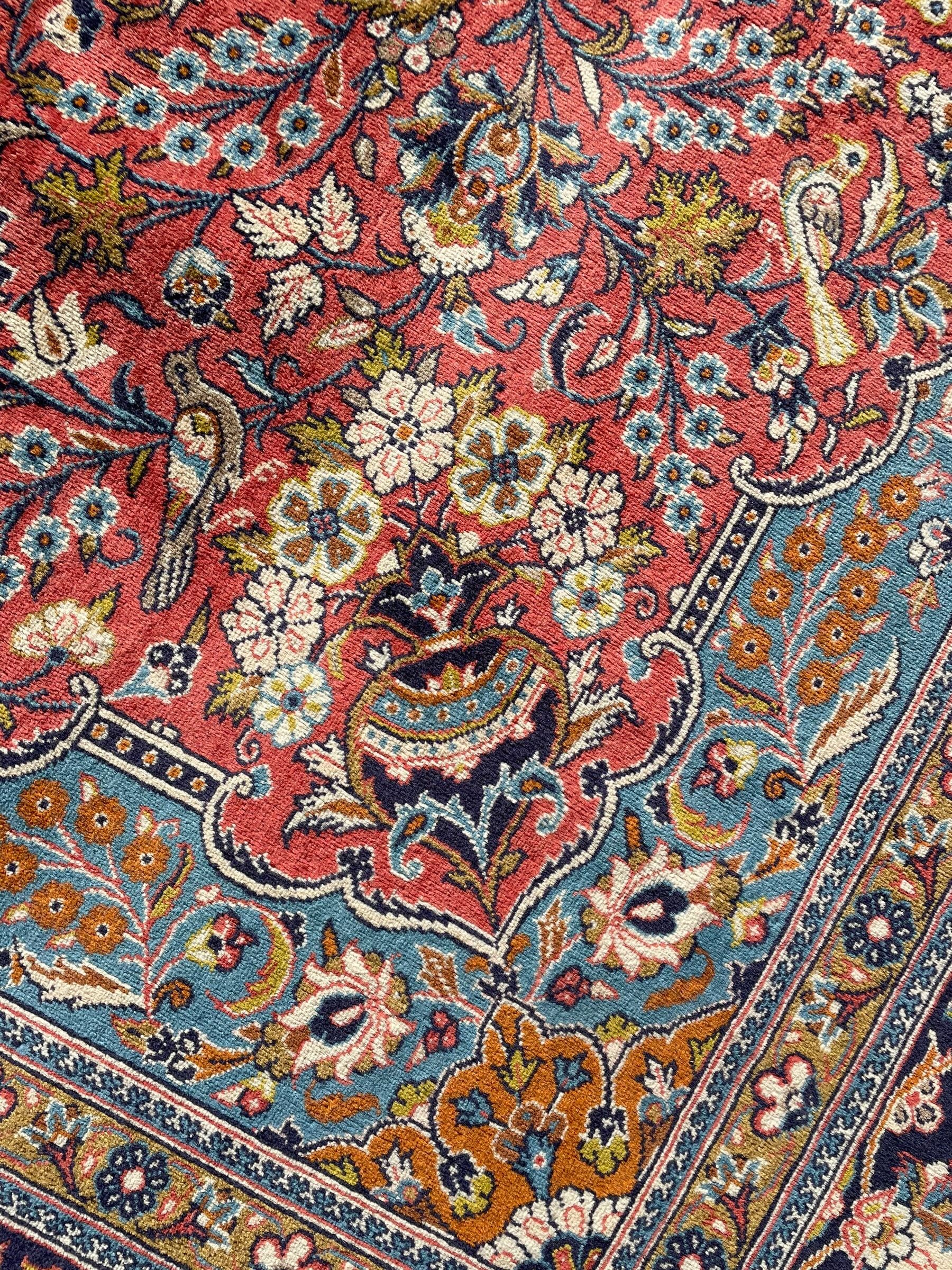 Persian Kashan peach ground rug, central rosette medallion surrounded by trailing branches and flower heads with bird motifs, light blue spandrels with further floral decoration, the main border with repeating palmettes and birds, within guard stripes