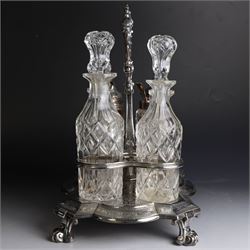 Victorian silver cruet stand, containing eight cut glass cruet bottles, four with silver covers, upon a shaped base with four scroll feet and loop handle, chased with floral and foliate decoration, the stand, base and bottle caps all hallmarked John, Edward, Walter & John Barnard, London 1872, one bottle with a matched silver cruet spoon, stand H30cm