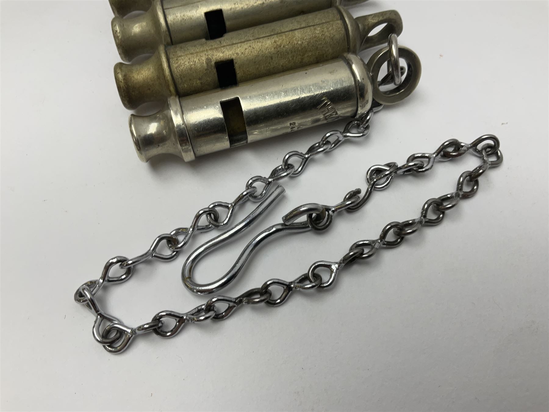 Three Hull City Police 'Metropolitan' whistles by J. Hudson 13 Barr Street Birminham, each with impressed collar number; another 'Metropolitan' police whistle with chain; and an ARP whistle by Hudson & Co with chain (5)