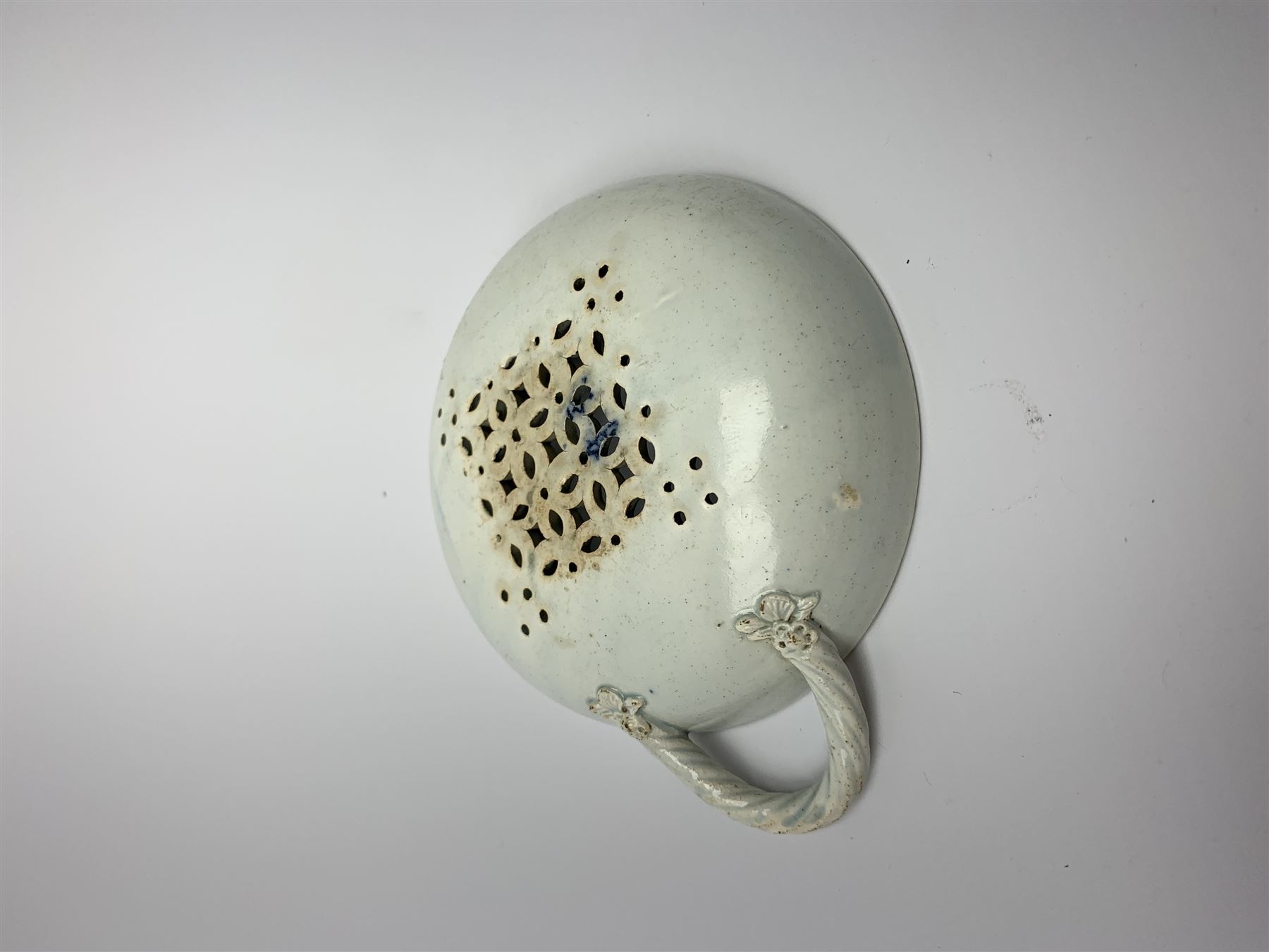 Late 18th/early 19th century Leeds Pottery egg drainer, the pierced bowl of circular form decorated with blue transfer printed floral spray and floral border, the twisted handle with foliate mounts, bowl D9cm