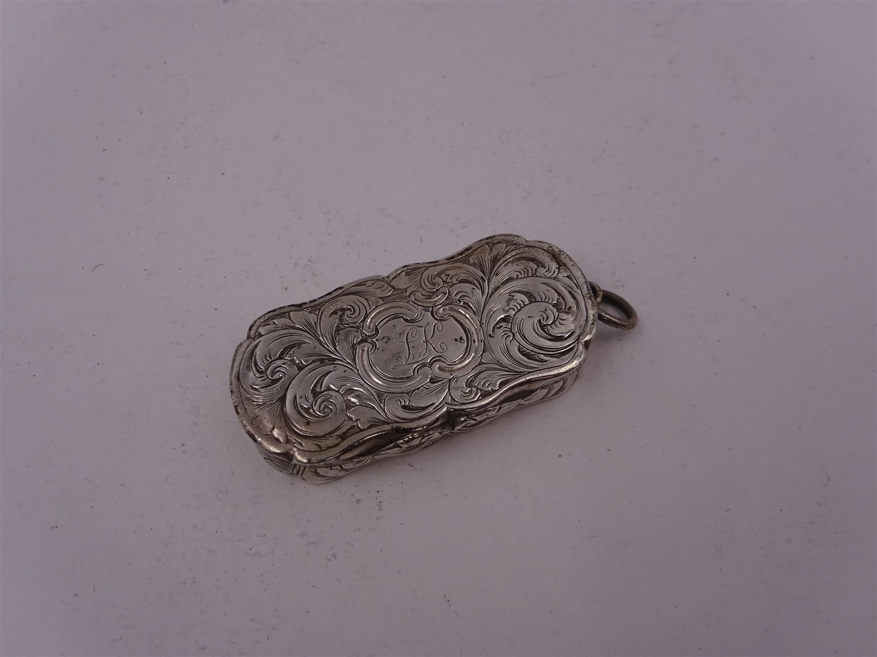 Victorian silver vinaigrette, of oval form with shaped rim, with engraved scrolling and foliate decoration and cartouche with initials, with foliate pierced gilt interior, hallmarked David Pettifer, Birmingham 1855, L4.3cm
