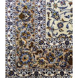 Central Persian Kashan hand-knotted carpet, ivory field with an all-over design of scrolling vines, lotus palmettes, and rosettes in shades of blue, gold, and brown within a blue ground border of palmettes and arabesques between multiple guard stripes