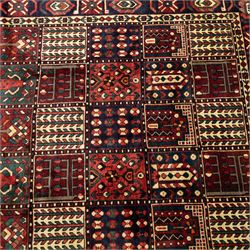 Bakhtiari wool rug, compartmented garden design field with panels of stylised trees, flowers and geometric motifs, enclosed by dark blue main border with repeating floral medallions and guard stripes