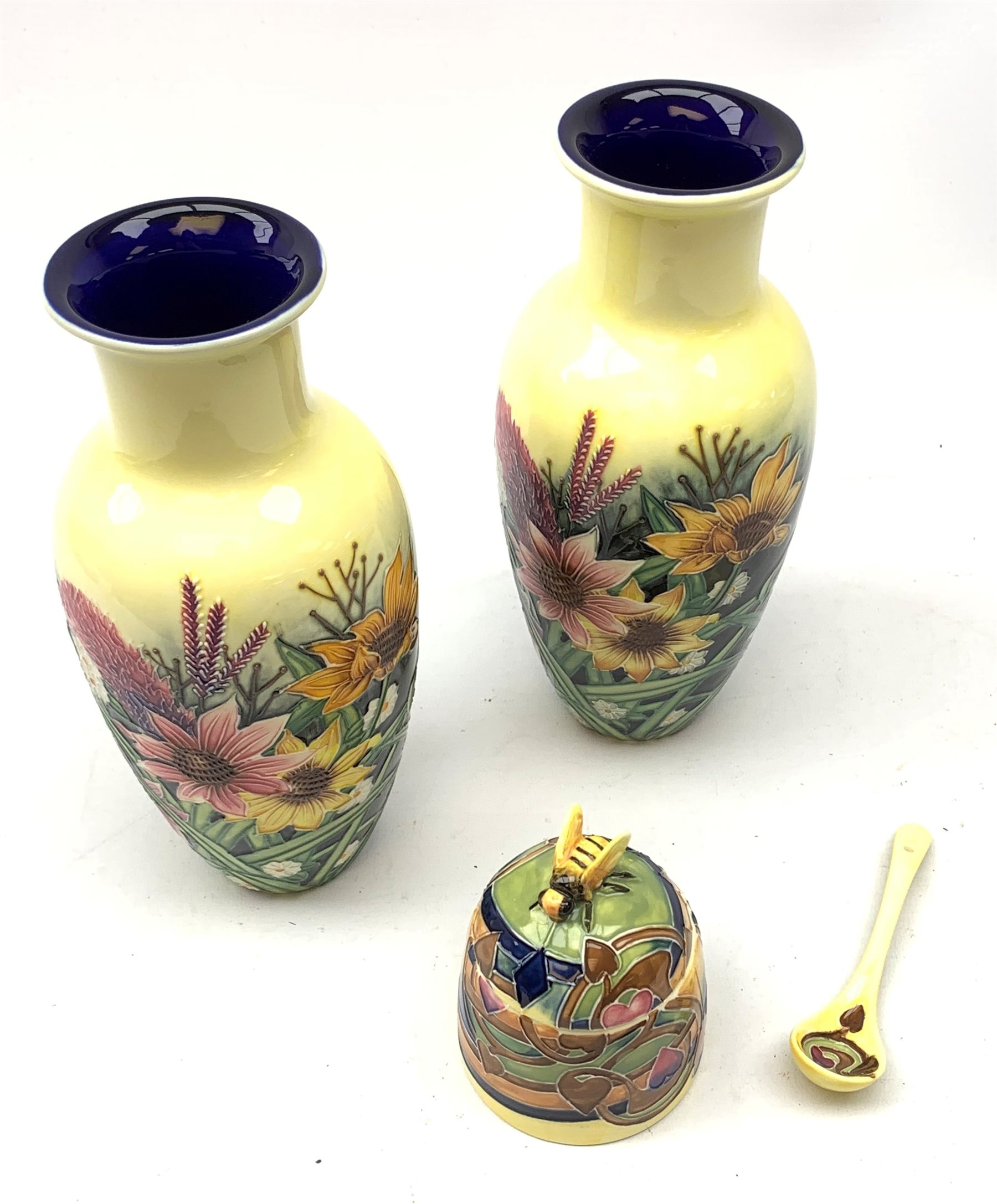 An Old Tupton Ware honey pot, of oval form with tube lined tendril decoration, the domed cover surmounted by a honey bee, with accompanying spoon, together with a pair of Old Tupton Ware vases, with tube lined sunflower decoration, H22cm, each with printed mark to base.