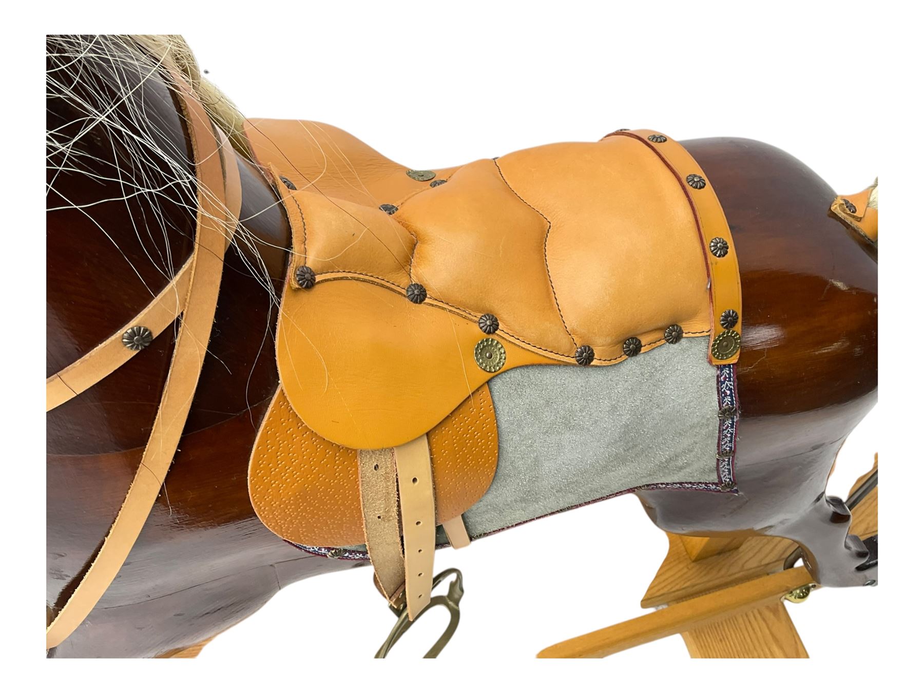 Contemporary carved wooden rocking horse, with leather saddle and bridle, horsehair mane and tail, raised on a pine stand with swing iron supports
