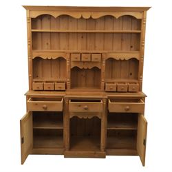 20th century country style waxed pine housekeeper’s cupboard, upper section with moulded cornice, shaped aprons and open shelving around central drawer arrangement, the lower section fitted with three drawers and two cupboards with panelled doors, raised on a plinth base